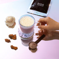 Mushroom Coffee with ingredients displayed - frothy drink in glass cup with functional mushrooms and powder on table